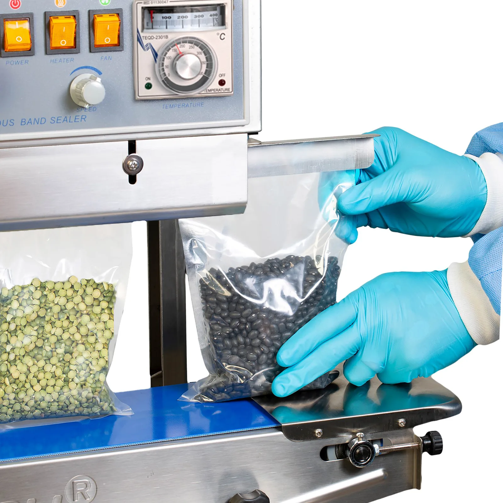 operador con guantes azules insertando bolsas transparentes sellables en una selladora vertical de banda JORES TECHNOLOGIES® llena de frijoles negros y lentejas verdes