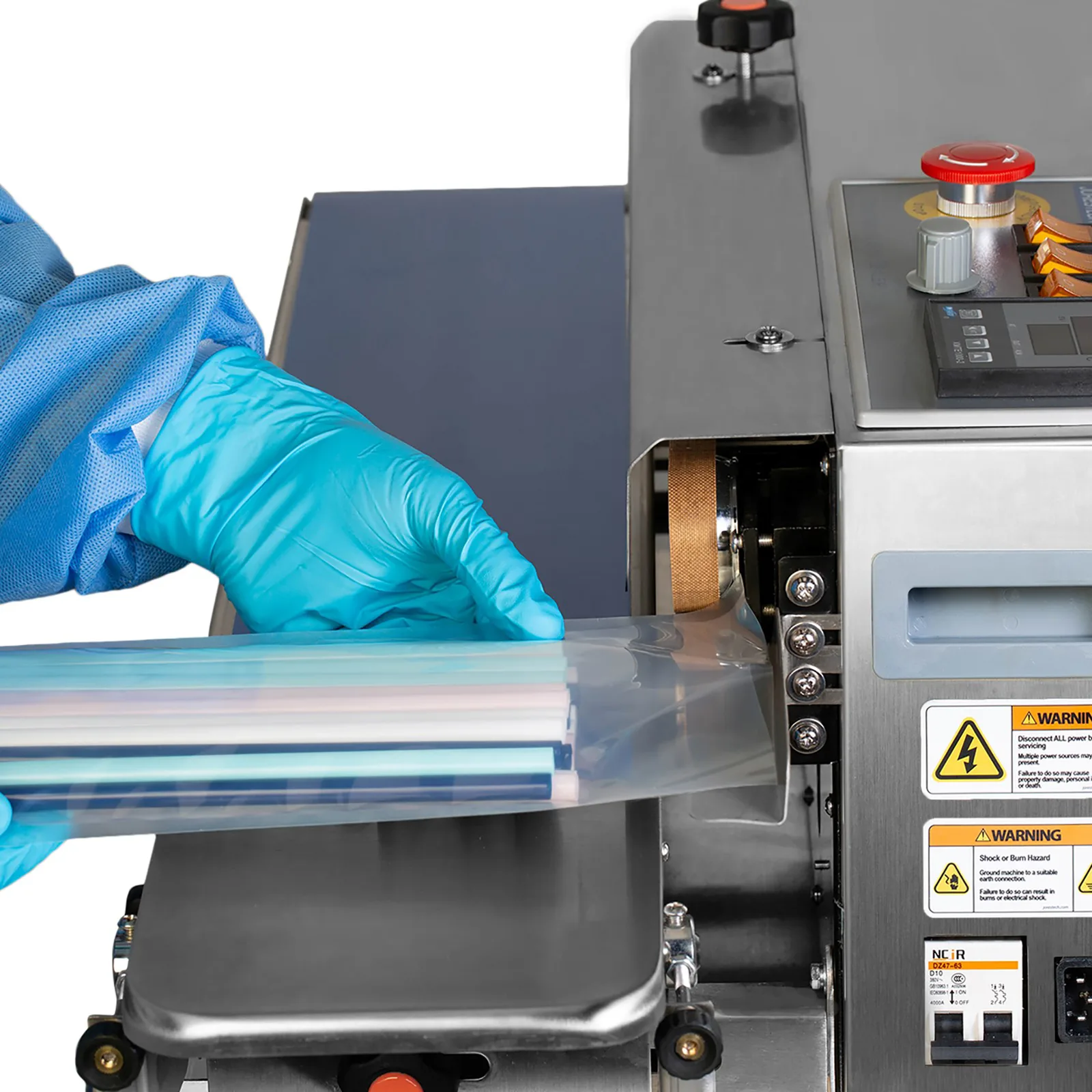 Trabajador insertando una bolsa transparente llena de paja multicolor en una selladora continua de bandas JORES TECHNOLOGIES® colocada horizontalmente para sellar bolsas cerradas
