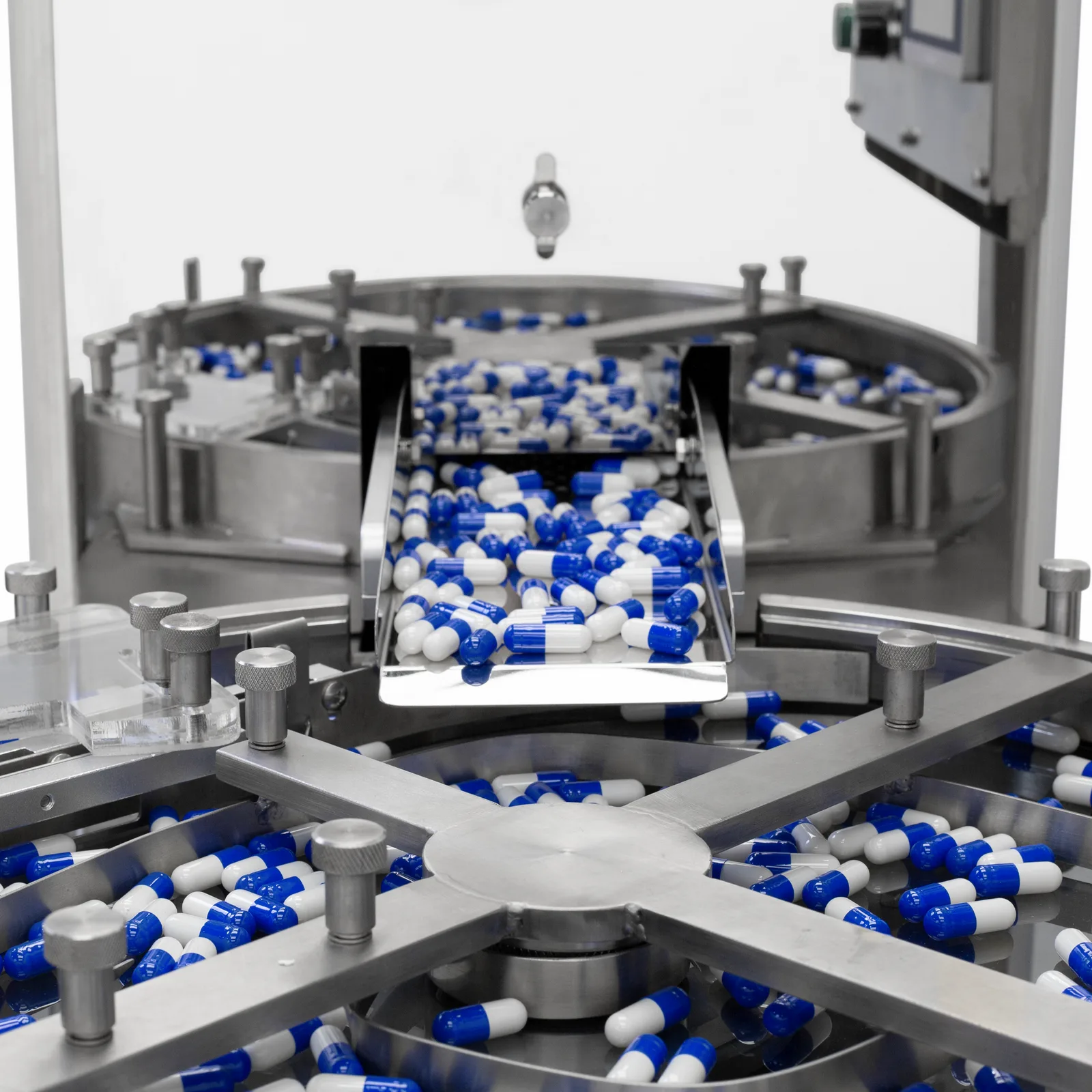 Cómo las pastillas salen de una gran tolva de acero inoxidable del contador de pastillas JORES TECHNOLOGIES® y caen en una bandeja circular segmentada.