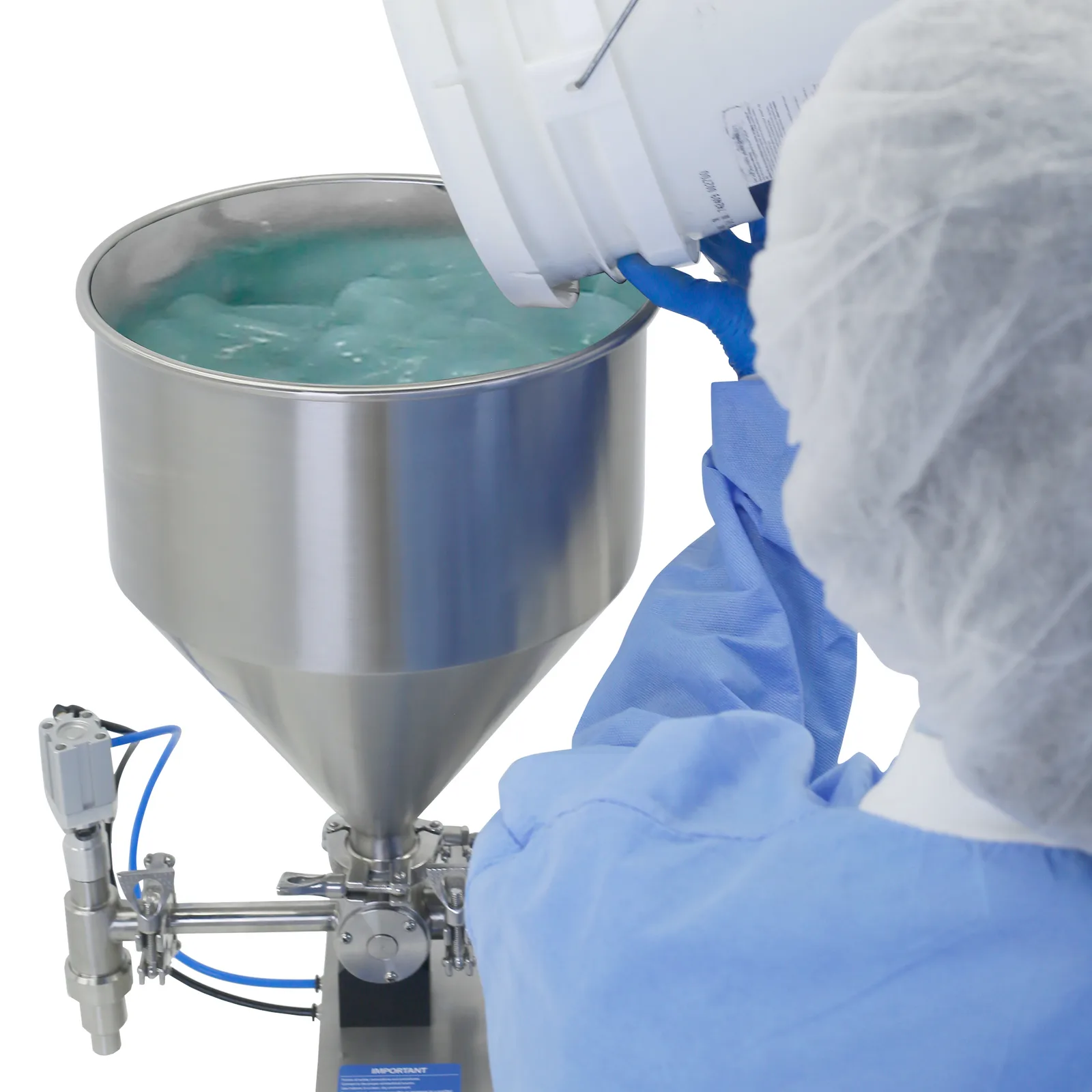 Un trabajador con ropa desechable y guantes junto a una llenadora de pistón. Está vertiendo un gel verde en la tolva de una llenadora de pistón de sobremesa JORES TECHNOLOGIES® para pasta