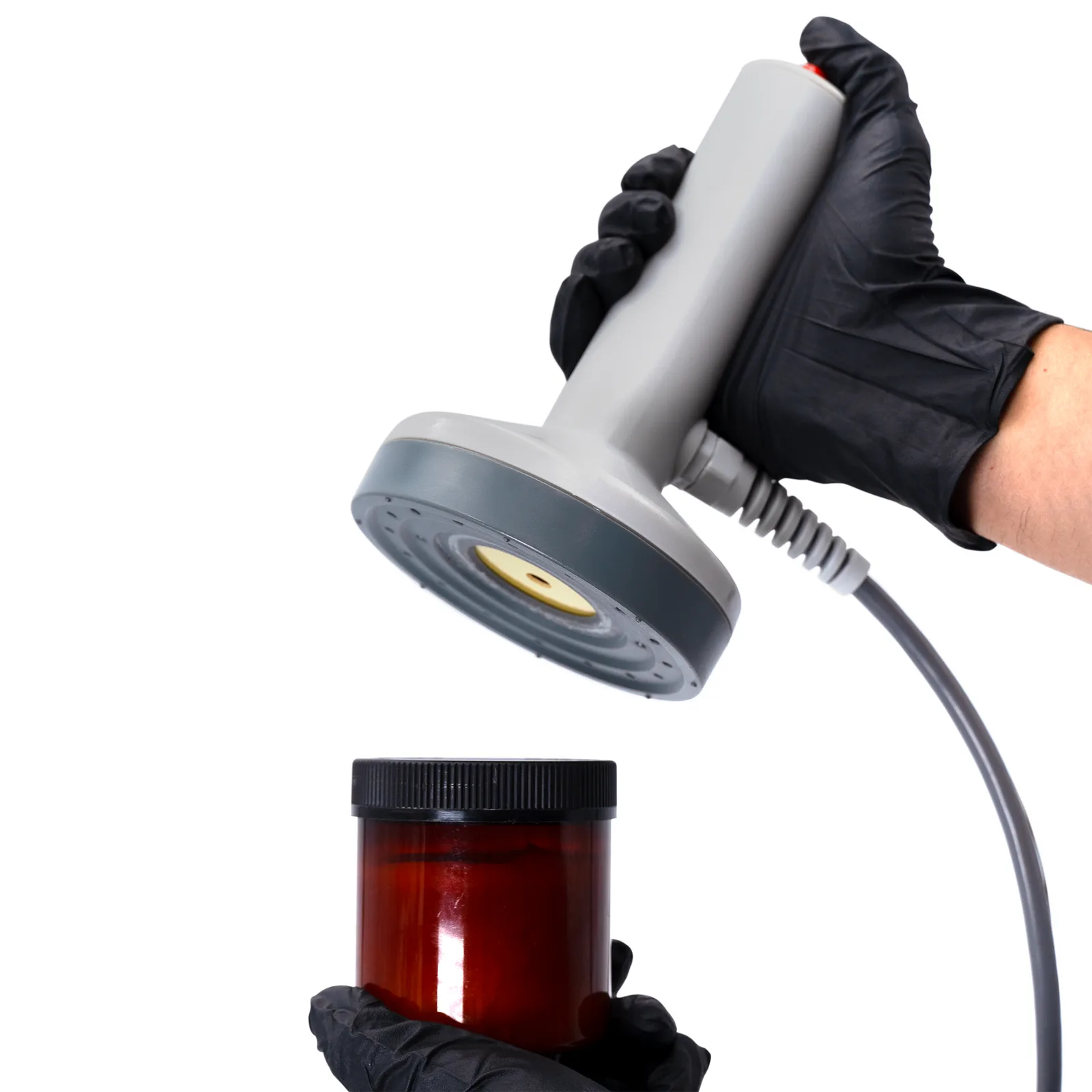 Trabajador sellando un recipiente de plástico con un liner de inducción usando una máquina selladora por inducción manual JORESTECH