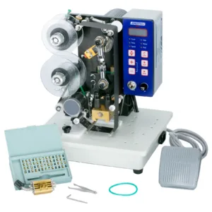 Frontal de la impresora digital semiautomática JORESTECH de estampado en caliente con foil y su pedal. La máquina tiene instalado el rodillo de tinta caliente. También se muestra el juego completo de tipos, las herramientas de instalación y un portatipos incluidos con la máquina