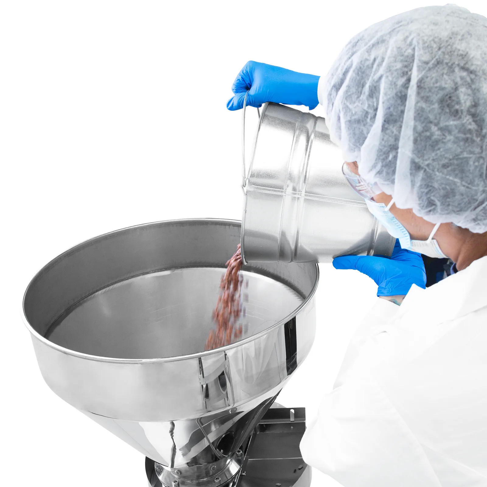 Un trabajador que lleva guantes de nitrilo azules y una variedad de equipos de protección personal dispensando frijoles en la tolva de acero inoxidable del llenador volumétrico semiautomático JORES TECHNOLOGIES®